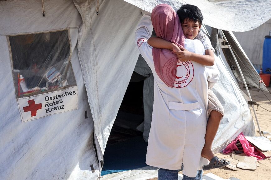 Palestinian paramedic Maha Wafi, 43, walks with her son Ahmed, six, into a tent in Khan Yunis in the southern Gaza Strip