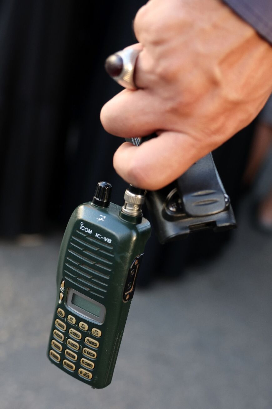 A man holds a walkie-talkie after removing its battery during a funeral in Beirut