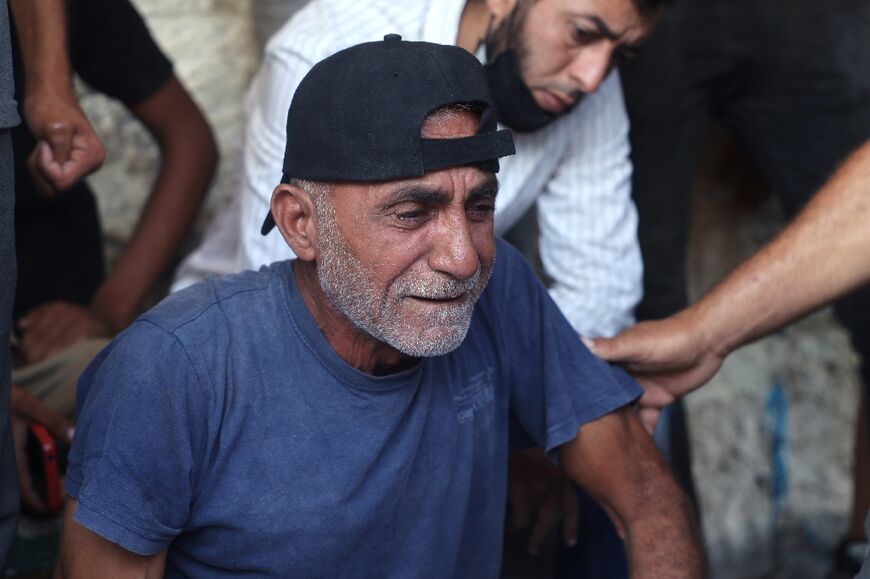 A Palestinian mourner is comforted after family members were killed in Deir el-Balah in the central Gaza Strip