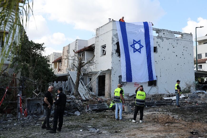 A large Israeli flag draped over a damaged building in Kiryat Bialik near Haifa after a rocket strike