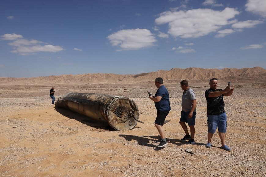 People take pictures near the remains of an Iranian missile in Israel's Negev desert near Arad 