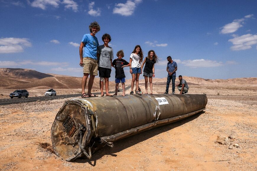 People stand on top of the remains of an Iranian missile in the Negev desert near Arad in southern Israel