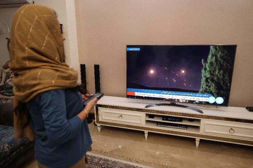 A woman in Tehran watches television coverage of Iran's missile attack on Israel