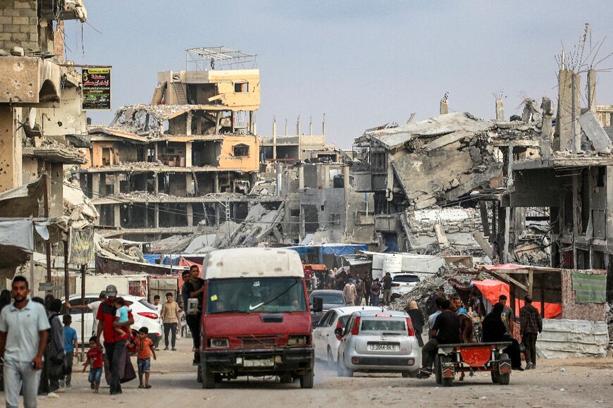 Vehicles move past destroyed buildings in Khan Yunis in the southern Gaza Strip 