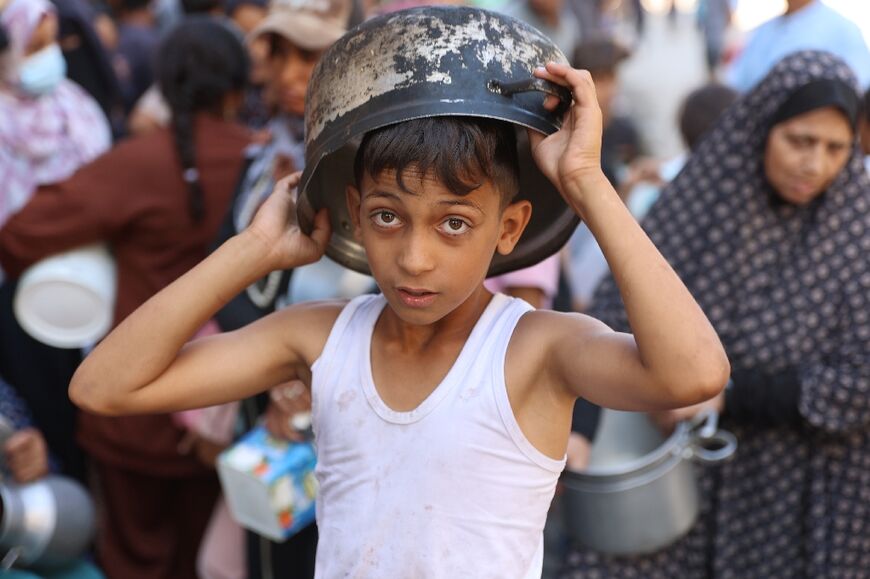 A displaced Palestinian boy queues to receive food rations in Gaza's Al-Shati refugee camp