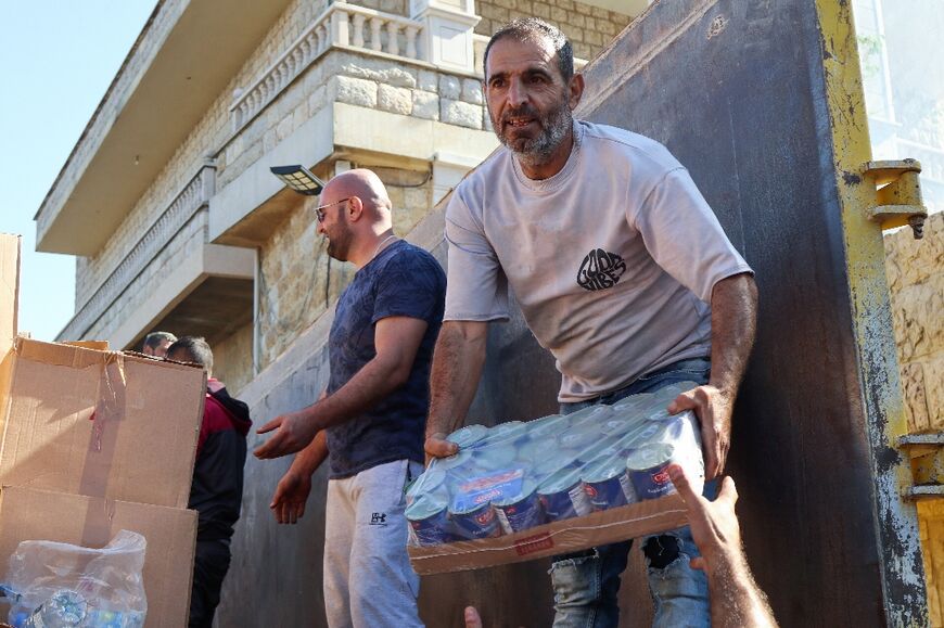 Residents of the southern Lebanese border village of Qlayaa who have decided to stay in their homes unload supplies provided through community initiatives