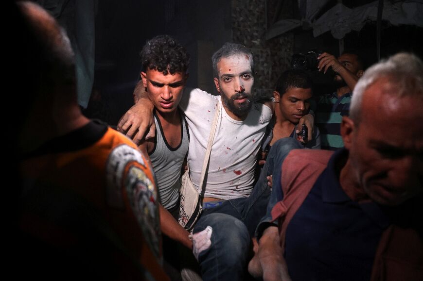 Palestinians help a man injured in an Israeli strike that targeted a mosque-turned-shelter in Deir el-Balah, central Gaza