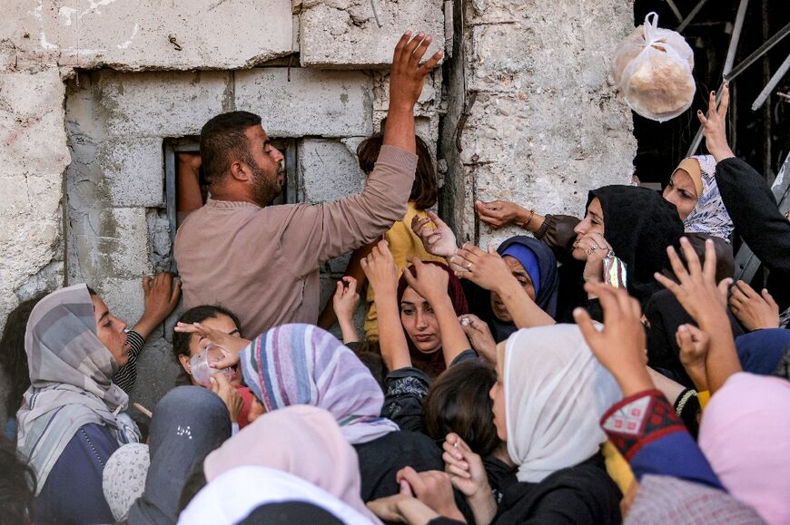 Dozens of people clamour for bread at a bakery in the Gaza city of Khan Yunis amid dire food shortages