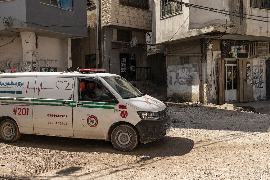 An ambulance drives through a damaged road in Jenin refugee camp, in the occupied West Bank