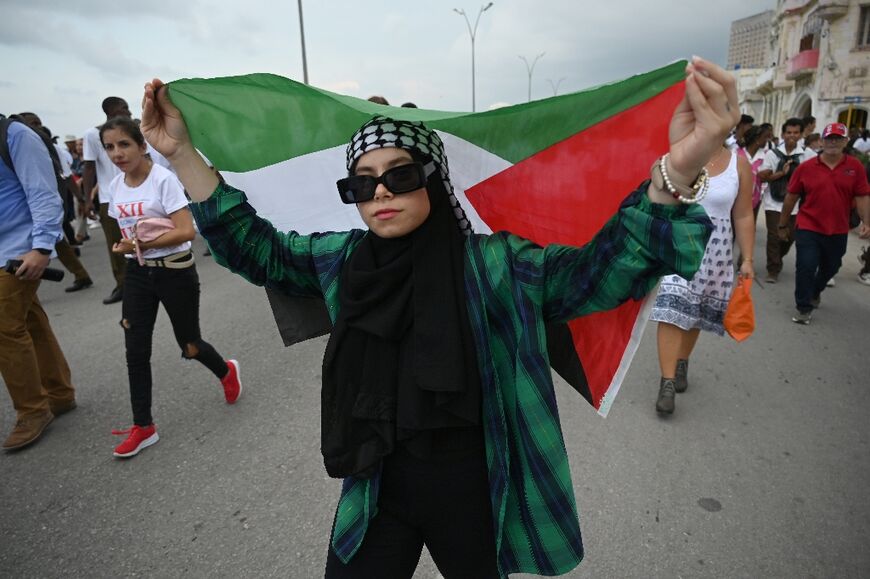 A woman holds a Palestinian flag as people march along Havana's waterfront during a pro-Palestinian rally