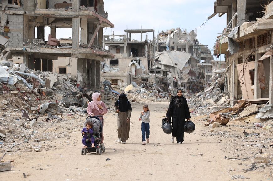 Palestinian women and children walk in the Shujaiya neighbourhood of Gaza City