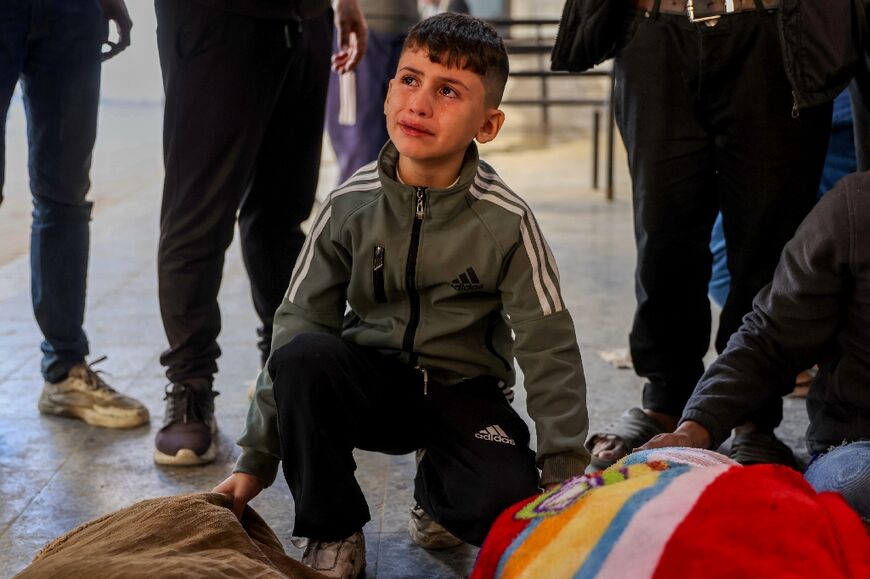 A Palestinian boy mourns over the bodies of victims of an Israeli strike at Al-Ahli Arab hospital in Gaza