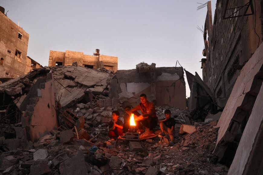 Palestinians warm themselves by a fire in the rubble of destroyed buildings in Bureij refugee camp, central Gaza 