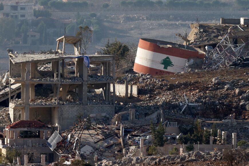 An Israeli flag hangs on a destroyed building while a Lebanese flag is painted on another in the southern Lebanese village of Meiss El-Jabal