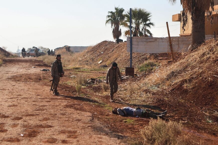 Fighters near a body in Atareb, in Syria's northern Aleppo province, where jihadists and allied factions are battling Syria's army in what a war monitor called the area's fiercest fighting in years