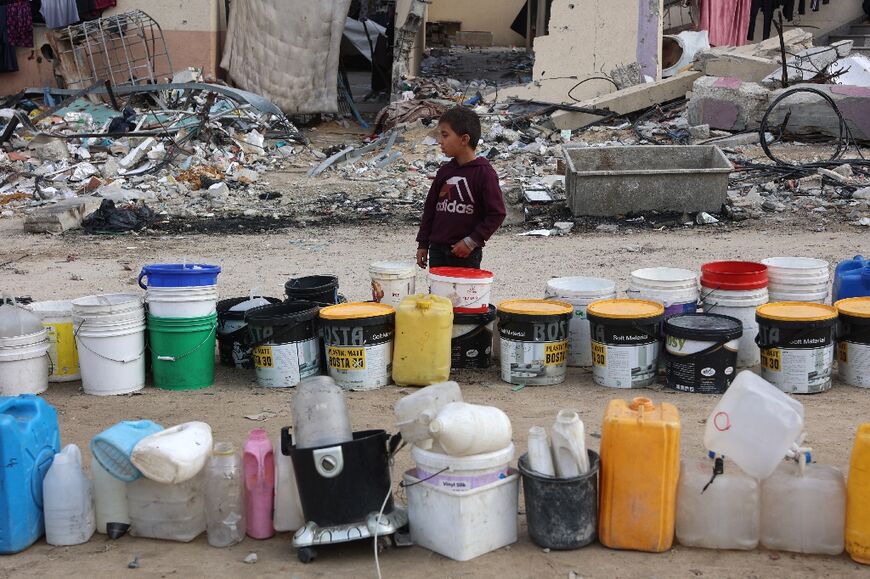 A Palestinian boy stands next to buckets, arranged and used to reserve a place in line, as people wait for water refill west of Gaza City in Gaza's north