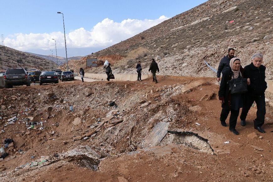 People fleeing Israeli bombardment in Lebanon skirt the edges of a crater