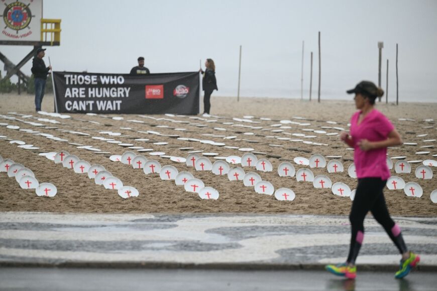 A woman jogs past 733 plates laid out on Copacabana Beach in Rio that represent the 733 million people who last year suffered from hunger