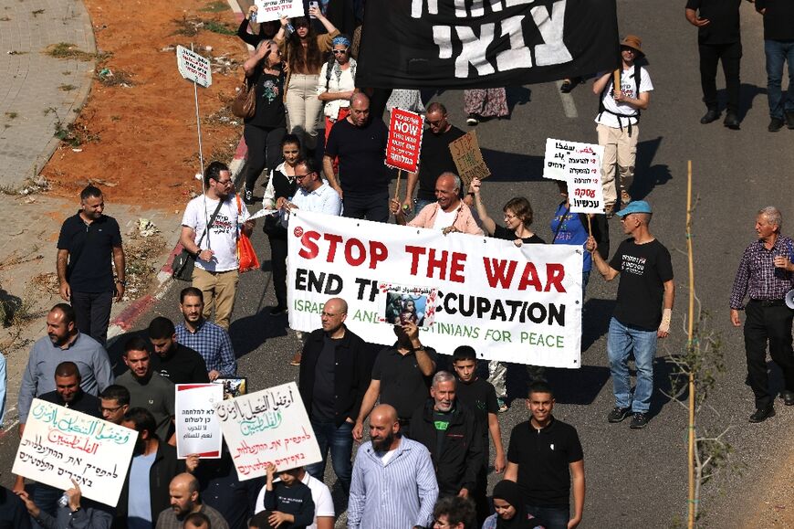 Demonstrators hold signs during a protest against the wars in Lebanon and the Gaza Strip, in the Arab-populated Israeli city of Umm al-Fahm