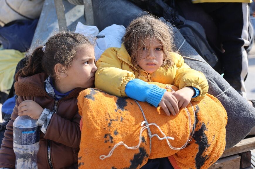 Palestinian children sit on the back of a donkey cart as an Israeli evacuation order forces their family to take to the road again in search of refuge.