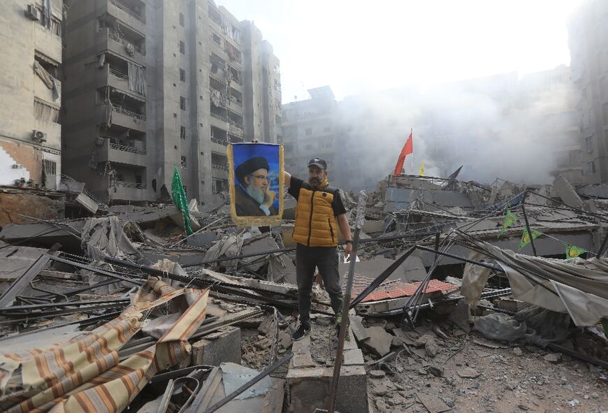 A man holds up a portrait of Hezbollah's slain leader Hassan Nasrallah in the ruins of the group's south Beirut bastion