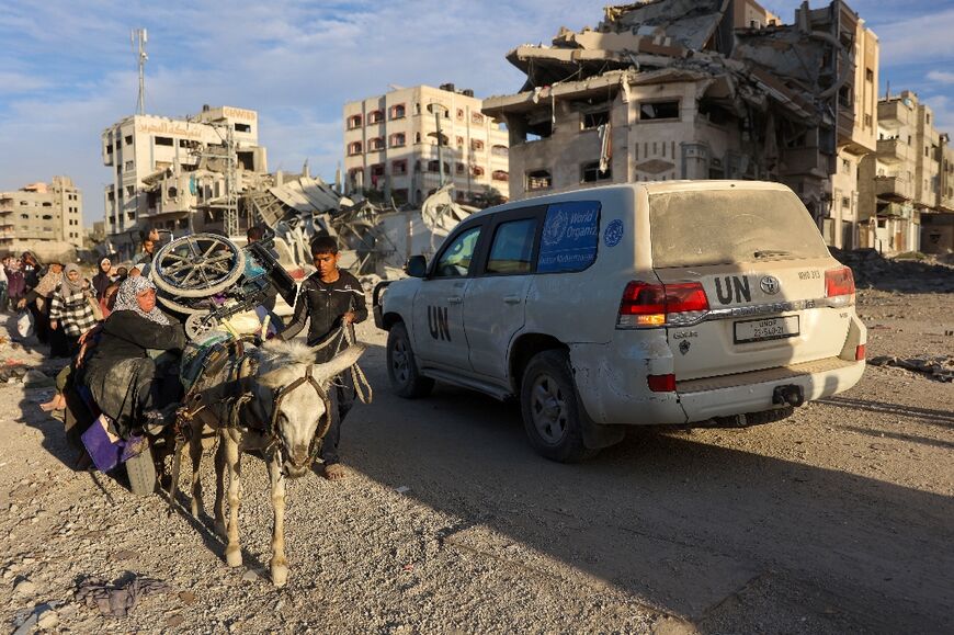 A convoy led by a United Nations vehicle drives past displaced Palestinians fleeing Beit Lahia, northern Gaza