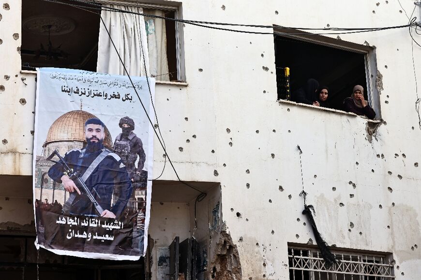 Palestinian women stare out the window of a shrapnel-pocked building after the latest Israeli raid in Jenin, a known stronghold for militant groups