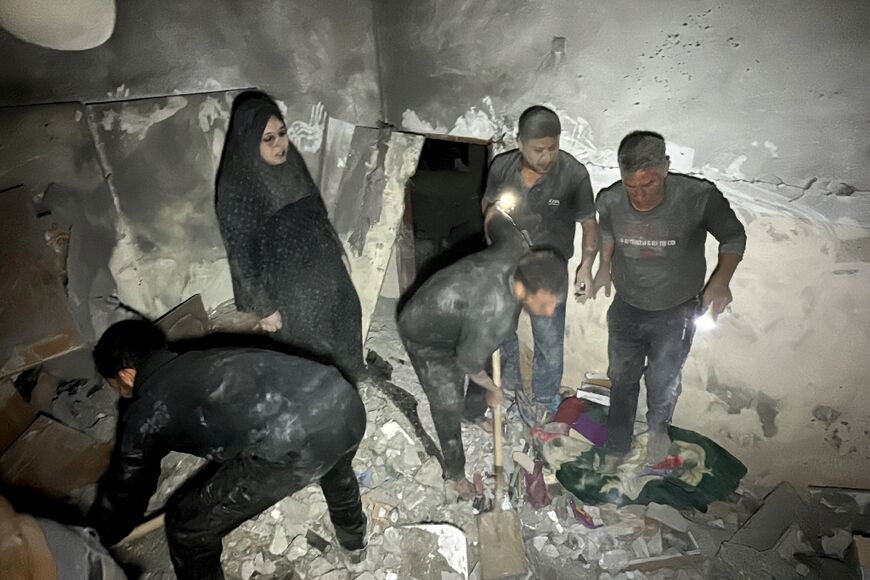 Civilians look for survivors in the rubble of a building following an Israeli strike near the Kamal Adwan hospital in Beit Lahia, in the northern Gaza Strip