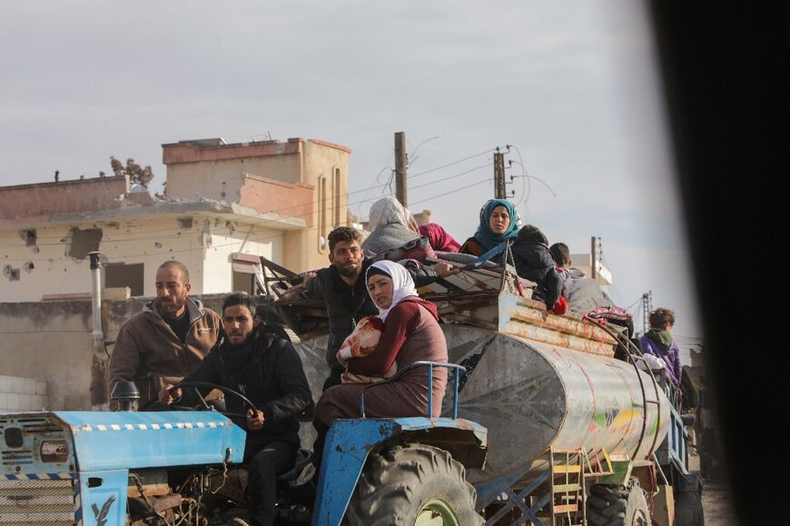 Displaced Syrians drive through Khan Shaykhun town as they evacuate to flee the Hama area