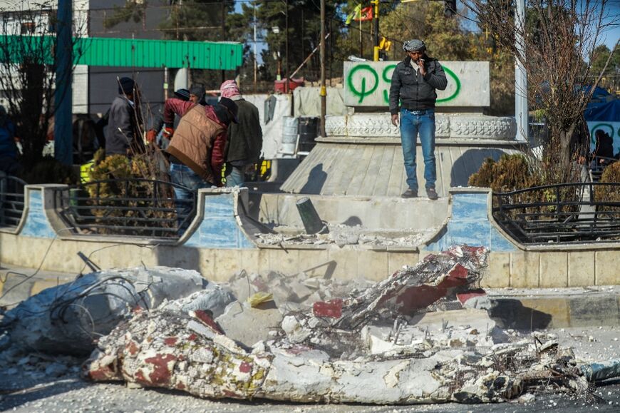 Workers in Qamishli, northeastern Syria, remove the rubble of a destroyed statue of the late Syrian president Hafez al-Assad, father of ousted president Bashar al-Assad