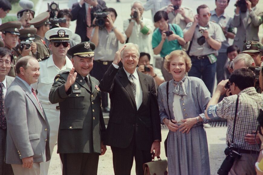 Former US president Jimmy Carter, accompanied by his wife Rosalynn, waves to journalists after he crosses over the border into North Korea on June 15, 1994