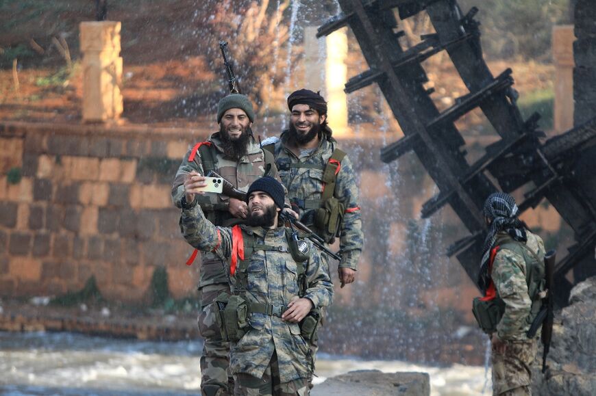 Rebel fighters take selfies alongside one of the landmark water wheels that dot the Orontes Valley around the central city of Hama.