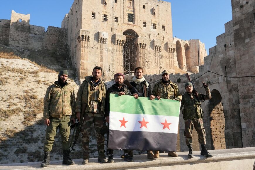 Anti-government fighters hold an opposition flag as they pose for a picture at the entrance of Aleppo's landmark citadel