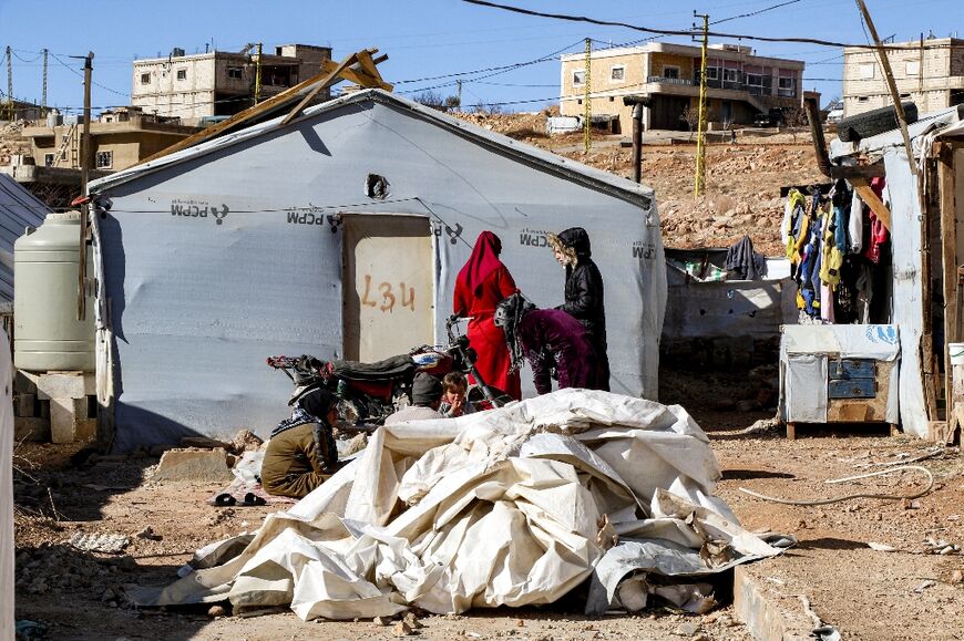 Syrian refugees stand outside a tent about to be dismantled at a camp in Arsal, eastern Lebanon, before returning to Syria