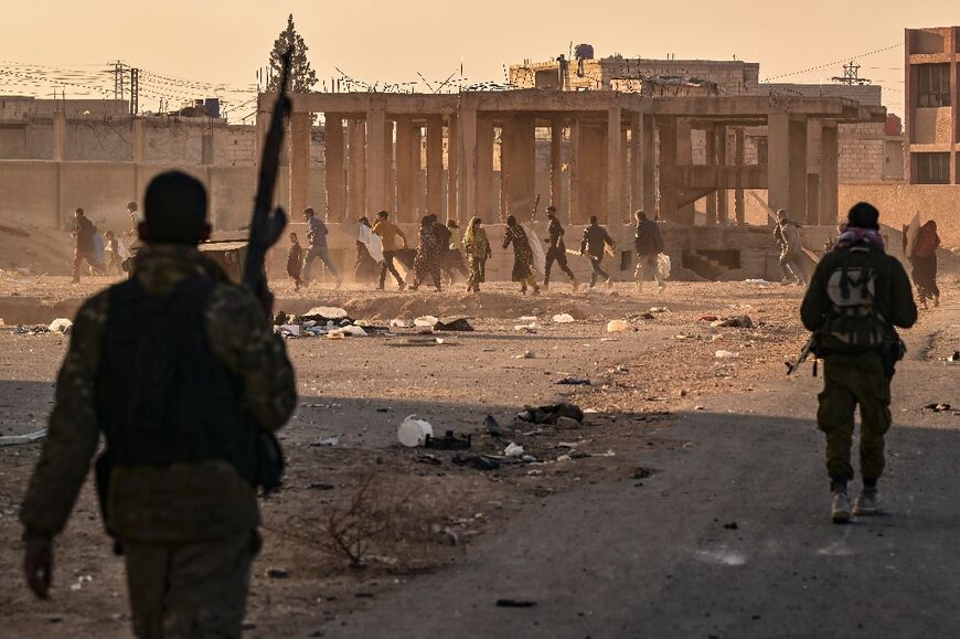 Rebel fighters fire in the air to disperse looters at an abandoned military housing complex in Damascus.