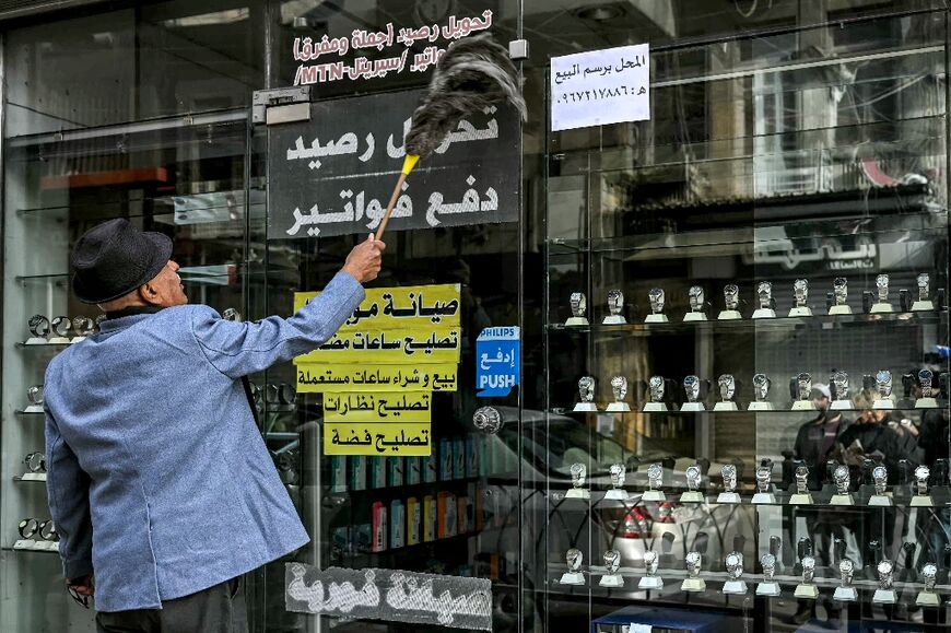 Ramadan Dali enthusiastically cleans his shop windows with his feather duster in Aleppo