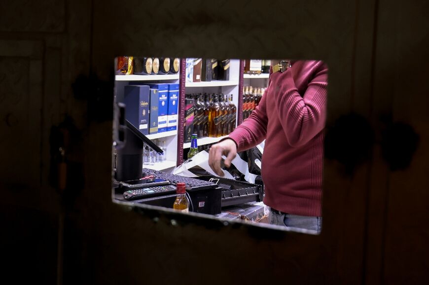 A man sells alcohol through a small window at a shop in Baghdad -- 'a game of cat and mouse' with authorities, one shopkeeper called it