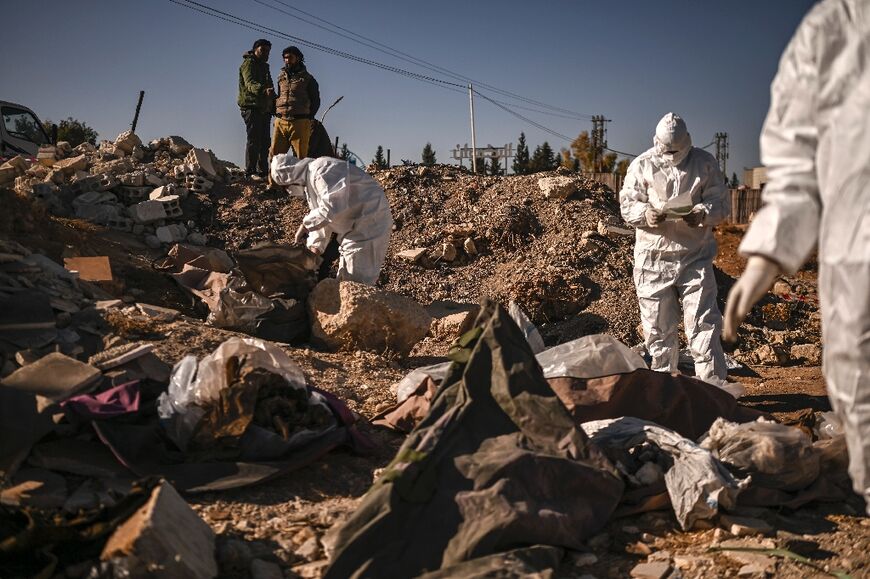 Members of Syria's White Helmets civil defence collect human remains at a mass grave