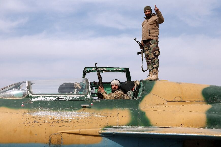 Rebel fighters inspect a captured Syrian air force jet at an airbase outside Hama