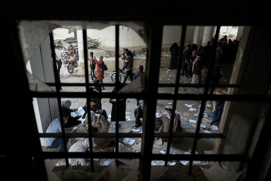 Syrians take photos and sort through papers at the Sednaya complex on December 11, 2024. Photo credit: Morhaf Kiwan.