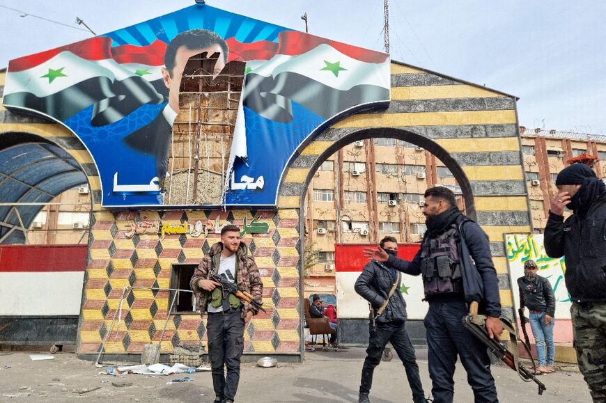 Locally-based fighters stand in front of a defaced portrait of Syrian President Bashar al-Assad in Syria's southern city of Daraa