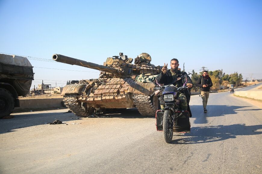 Rebel fighters pass an abandoned army military on the road southeast from Aleppo.