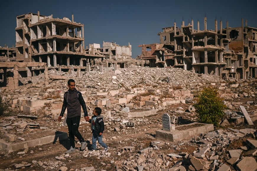 People look for graves of relatives in a damaged cemetery at the Yarmuk Palestinian refugee camp south of Damascus