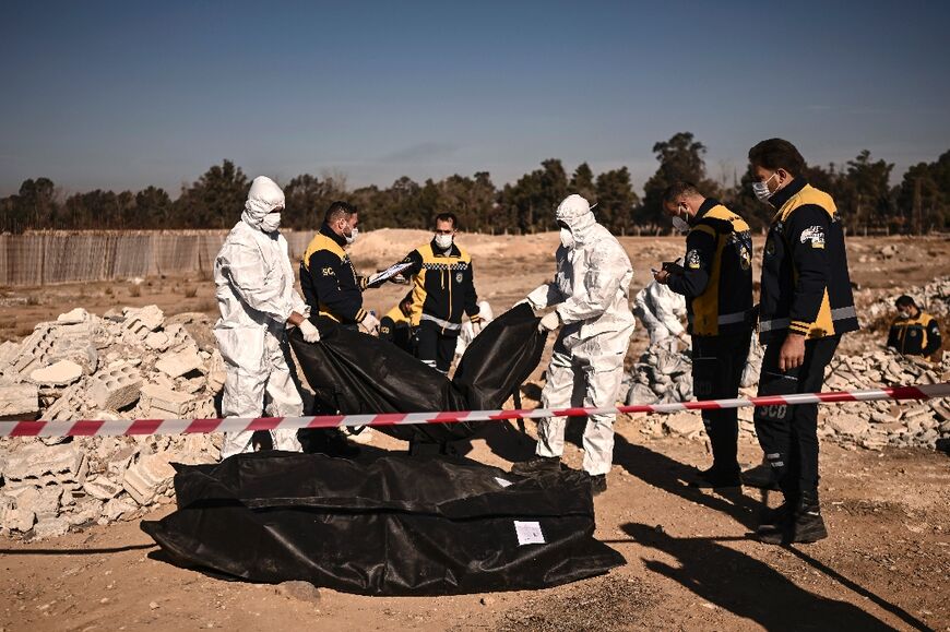 A Civil Defence team moves bags containing human remains