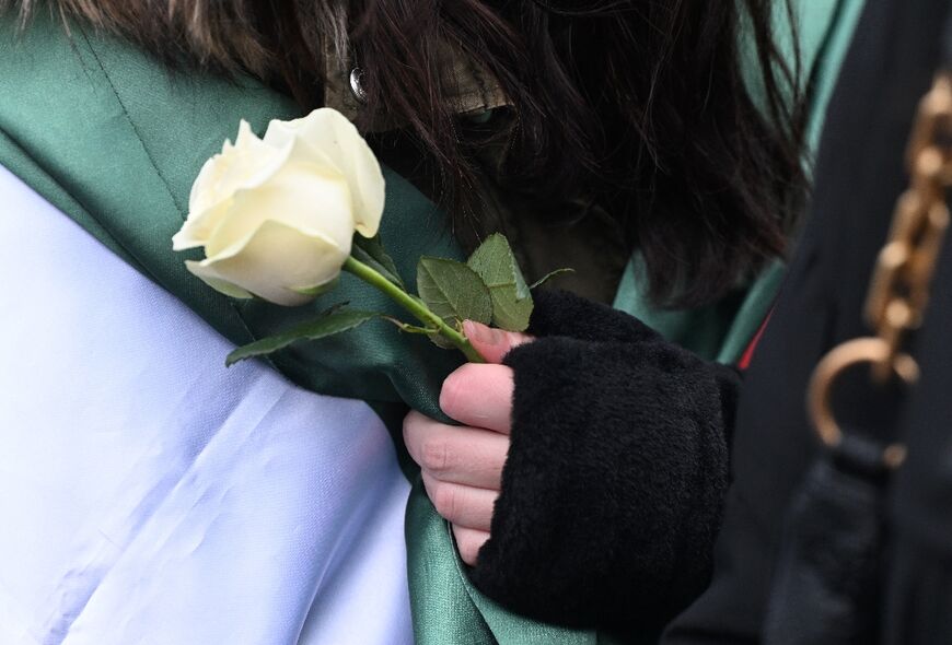 A woman wrapped into a Syrian flag holds a white rose in Berlin