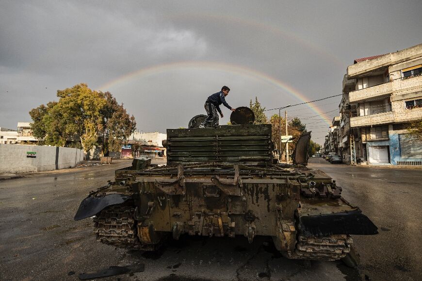 A Syrian child plays on a damaged tank in Homs 