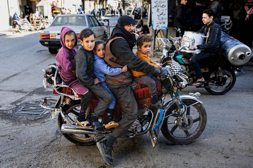 A man and his children ride on a motorcycle in Douma, east of the Syrian capital Damascus