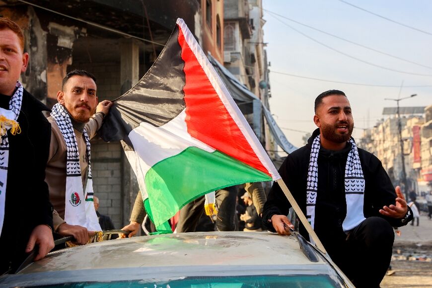 Men ride in a car adorned with a Palestinian flag along a street in Gaza City to celebrate the truce