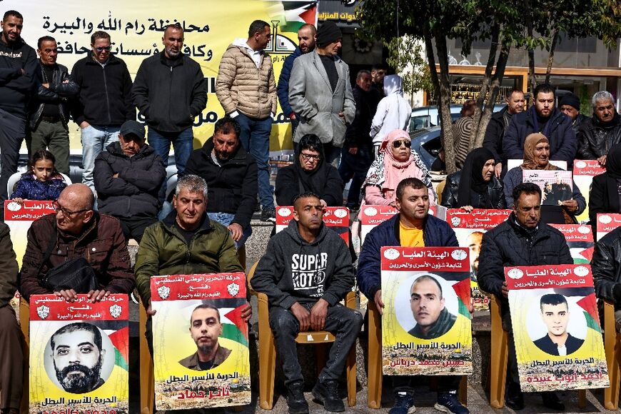 People lift placards bearing portraits of Palestinians currently detained by Israel, during a protest in solidarity with them in Ramallah in the occupied West Bank