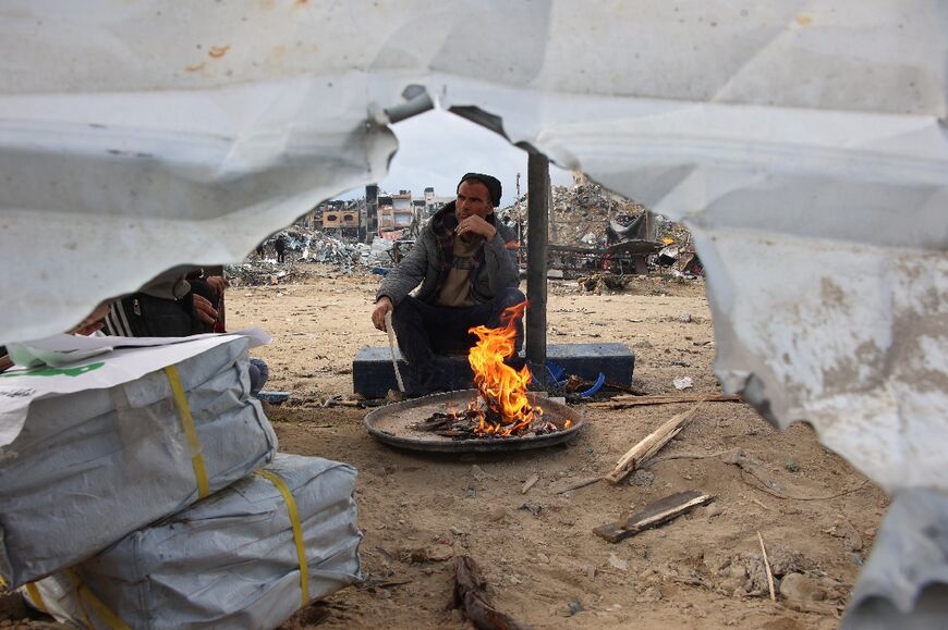 A returning resident of the north Gaza town of Jabalia lights a fire outside a makeshift tent.